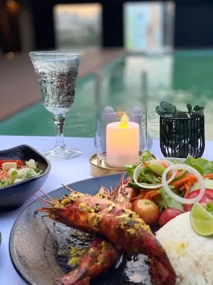 a plate of food with shrimp and rice and a candle at Zayn Hotel Bangkok - Airport Link Access in Bangkok