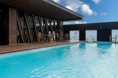 a swimming pool with chairs and tables on a building at Zayn Hotel Bangkok - Airport Link Access in Bangkok