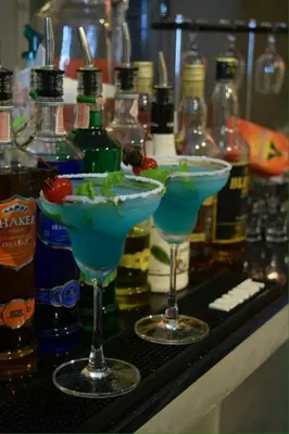 two cocktails on a counter with bottles of alcohol at U431 Chaengwattana in Nonthaburi