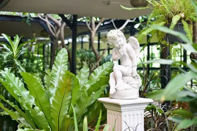 a statue of a girl sitting on a pedestal in a garden at Grand Howard Hotel Bangkok in Bangkok