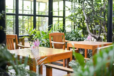 two wooden tables and chairs in a greenhouse at Grand Howard Hotel Bangkok in Bangkok