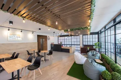 an office lobby with tables and chairs and plants at Let's Zzz Bangkok in Bangkok