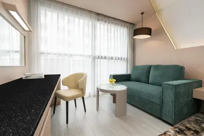 a living room with a green couch and a table at Hyatt Place Bangkok Sukhumvit 1 in Bangkok