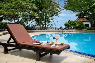 a lounge chair next to a swimming pool at Riverine Place Hotel and Residence in Nonthaburi