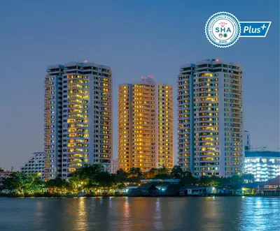 two tall buildings next to a body of water at Riverine Place Hotel and Residence in Nonthaburi