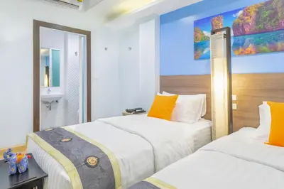 a bedroom with two beds and a painting on the wall at 4M Pratunam Hotel in Bangkok