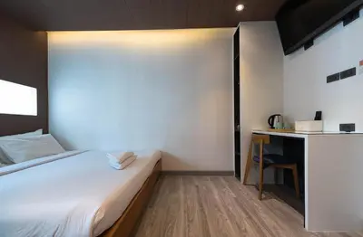 a small bedroom with a bed and a desk at The Period Pratunam in Bangkok