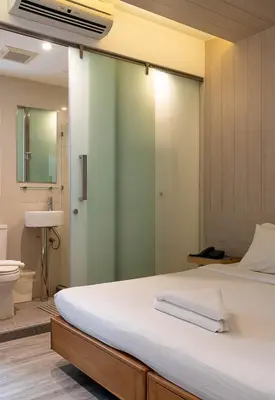 a bedroom with a large bed with a glass wall at The Period Pratunam in Bangkok