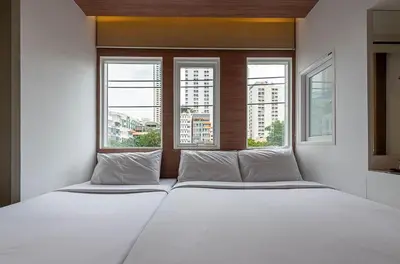 a white bed in a room with two windows at The Period Pratunam in Bangkok
