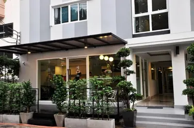 a store front of a white building with potted plants at Delight Residence in Bangkok
