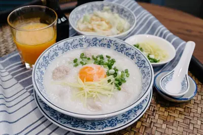 a bowl of soup and a glass of orange juice at Baan Vajra in Bangkok