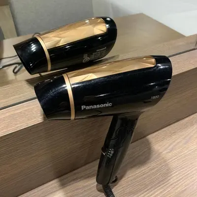 a black and gold hair dryer sitting on a counter at Toptel Thaphra - ท็อปเทล ท่าพระ in Bangkok