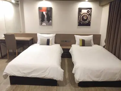 two beds in a room with a table and a picture at Toptel Thaphra - ท็อปเทล ท่าพระ in Bangkok
