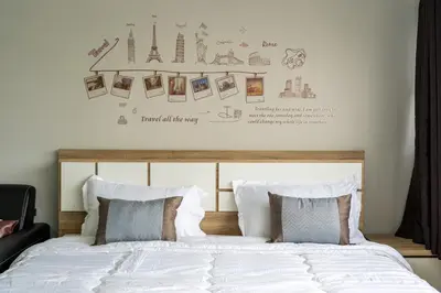 a bedroom with a bed with white sheets and pictures on the wall at Popular Condo Muangthong by Khun Eve in Nonthaburi
