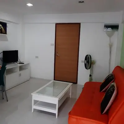 a living room with a red couch and a coffee table at SLT Apartment Bangkok in Bangkok