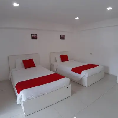 two beds with red pillows in a white room at SLT Apartment Bangkok in Bangkok