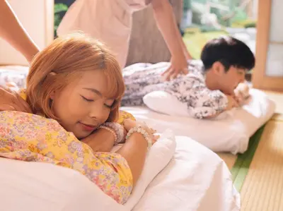 a young girl sleeping on a bed with a boy at MAYU Bangkok Japanese Style Hotel in Bangkok