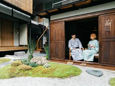 a man and woman sitting on a bench outside of a house at MAYU Bangkok Japanese Style Hotel in Bangkok