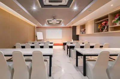 a conference room with tables and chairs and a whiteboard at Samyan Serene Hotel in Bangkok