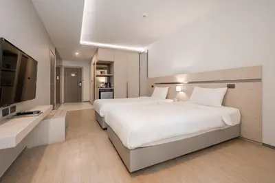 a bedroom with a large white bed and a flat screen tv at Samyan Serene Hotel in Bangkok