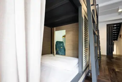a small bed in a room with a mirror at Warm Window Silom in Bangkok
