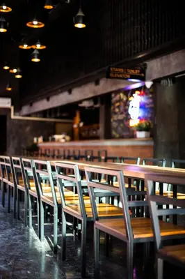 a row of chairs in a restaurant with a bar at BED STATION Hostel Khaosan in Bangkok
