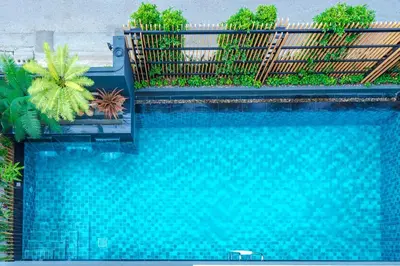 a blue swimming pool with a fence and plants at Penyos Residence in Bangkok