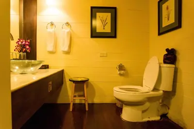a yellow bathroom with a toilet and a sink at Arun Residence in Bangkok