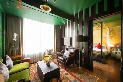 a living room with a bed and a couch and a chair at Dhevi Bangkok Hotel in Bangkok