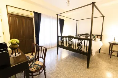 a bedroom with a canopy bed and a table and chairs at SSIP Boutique Dhevej Bangkok in Bangkok
