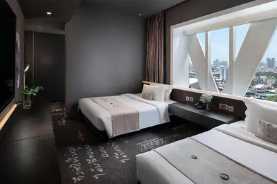 two beds in a room with a large window at Mode Sathorn Hotel in Bangkok