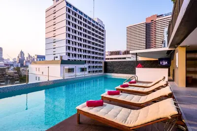a pool on the roof of a building with lounge chairs at GLOW Sukhumvit 5 in Bangkok
