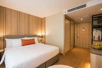 a bedroom with a large white bed and a kitchen at The Key Premier Hotel Sukhumvit Bangkok in Bangkok
