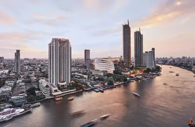 a river in a city with tall buildings at The Peninsula Bangkok in Bangkok