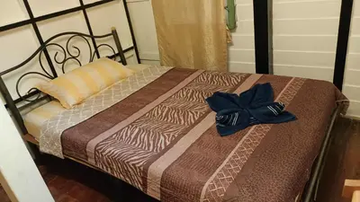 a bed with a brown comforter with a blue bow on it at New Phiman Riverview Guesthouse in Bangkok