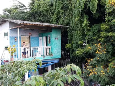 a man standing on the balcony of a blue house at New Phiman Riverview Guesthouse in Bangkok