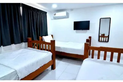a room with two beds and a tv in it at Papa Ji Hotel and Restaurant in Bangkok