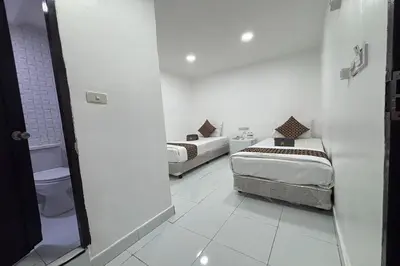 a white room with two beds and a toilet at Papa Ji Hotel and Restaurant in Bangkok