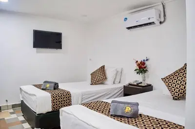 a hotel room with three beds and a tv at Papa Ji Hotel and Restaurant in Bangkok