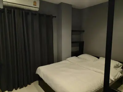 a bedroom with a white bed with a black curtain at Ratch66 Huai Khwang MRT in Bangkok