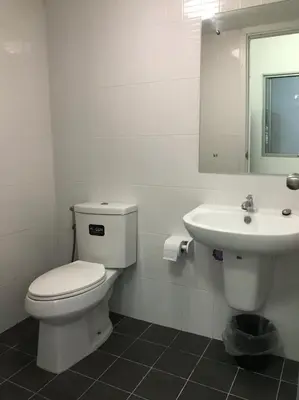 a white bathroom with a toilet and a sink at NIDO Guest House in Ban Bang Phang