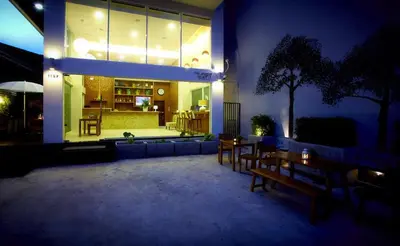 a patio with wooden tables and chairs at night at Loft 77 in Bangkok