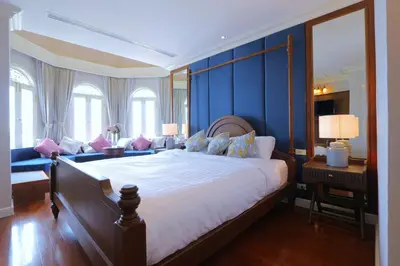 a bedroom with a large bed with blue walls at Hiranyakul House Riverside in Bangkok