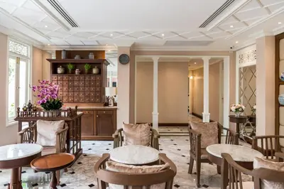 a dining room with tables and chairs and a kitchen at Hiranyakul House Riverside in Bangkok