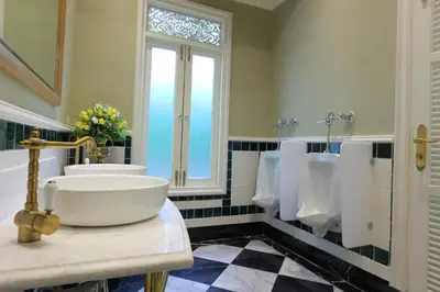 a bathroom with a sink and urinals and a window at Hiranyakul House Riverside in Bangkok