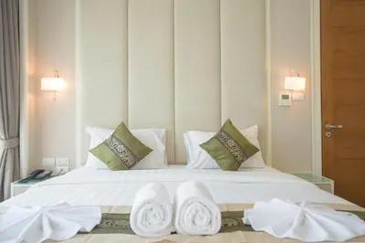 a bedroom with a white bed with towels on it at GM Serviced Apartment in Bangkok