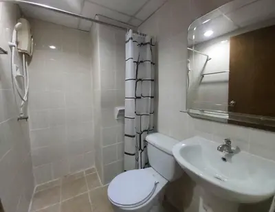 a white bathroom with a toilet and a sink at Hotel Paraiso in Bangkok