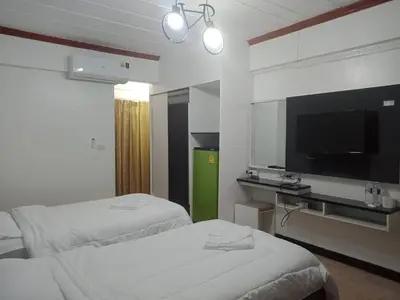 a hotel room with two beds and a flat screen tv at Hotel Paraiso in Bangkok