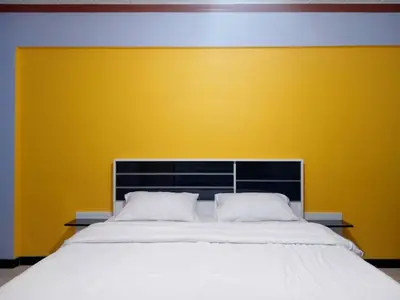 a bedroom with a large bed with a yellow wall at Hotel Paraiso in Bangkok