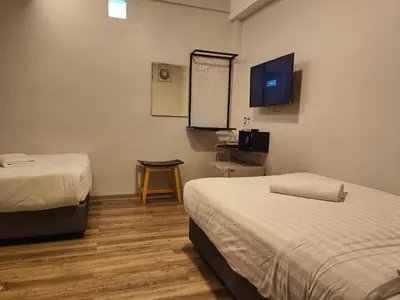 a room with two beds and a flat screen tv at Kim Korner Hotel in Bangkok